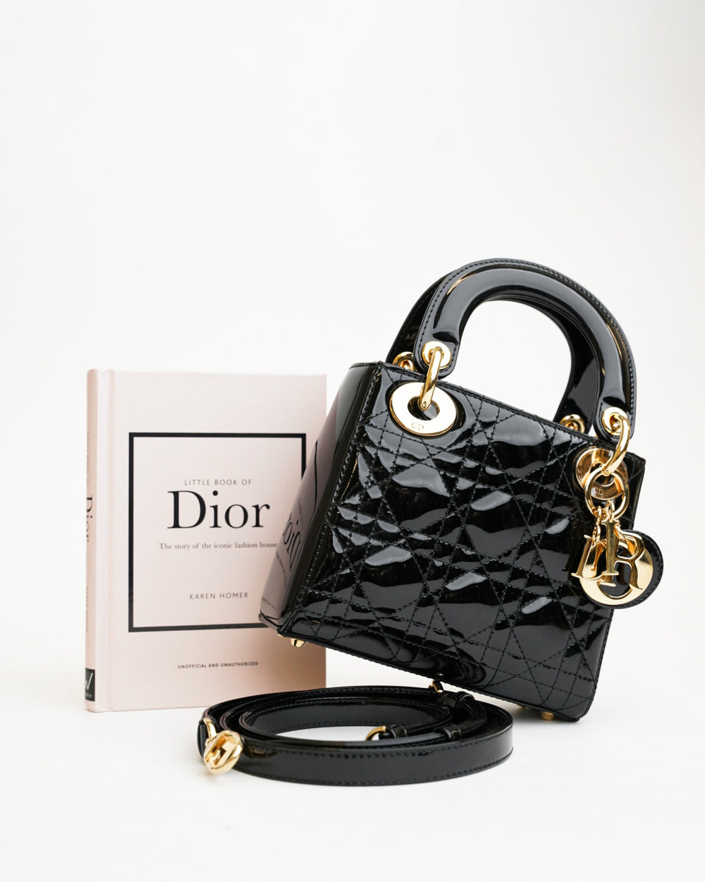 A black patent Lady Dior bag beside a Dior book
