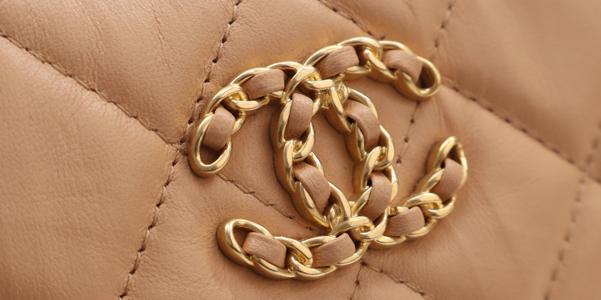Close-up of the gold chain CC on a quilted Chanel 19 bag