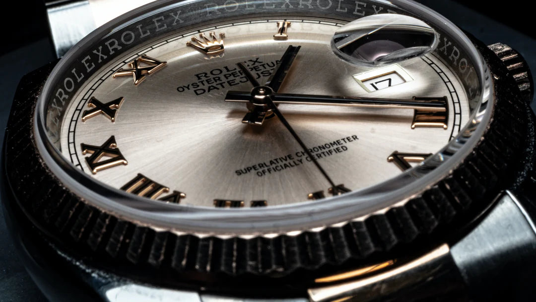 Close-up of a Rolex watch face with gold Roman numerals and a date window at three o'clock