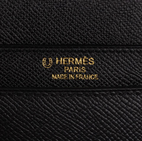 Close up of black textured leather Hermès item with gold Hermès Paris Made in France stamp and horseshoe symbol