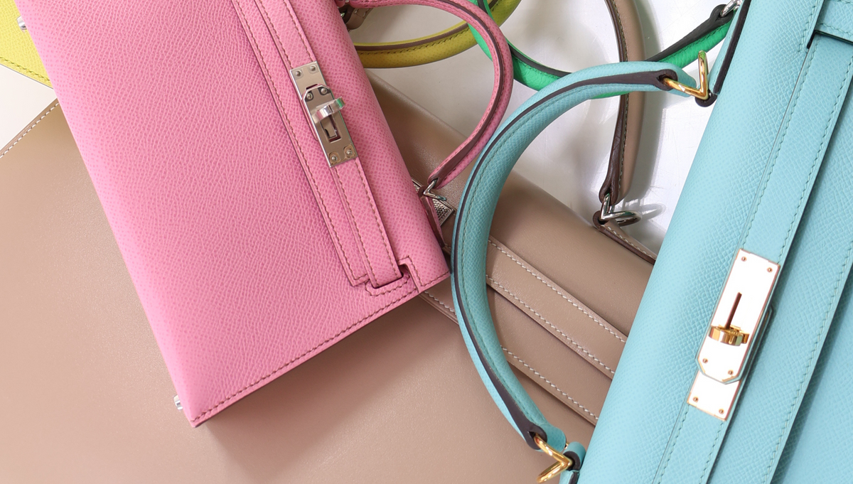 Three luxury handbags in pink, beige, and light blue leather with silver and gold hardware
