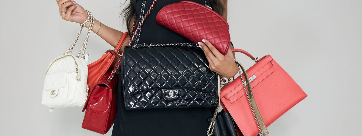 Woman holding multiple luxury handbags including white Chanel quilted leather bag and black Chanel classic flap bag