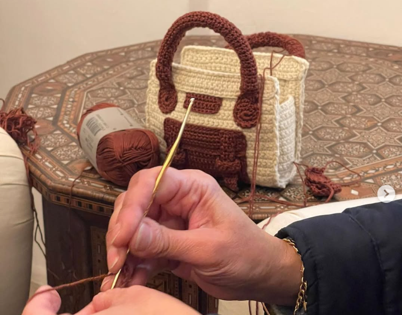 Chloe x Sarah's Bag crochet handbag in cream and brown with gold hardware on a patterned table.