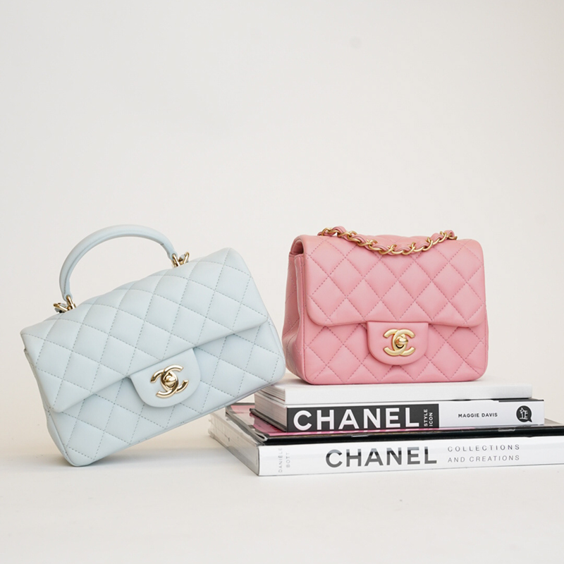Light blue and pink Chanel quilted leather handbags with gold hardware, displayed on white books.