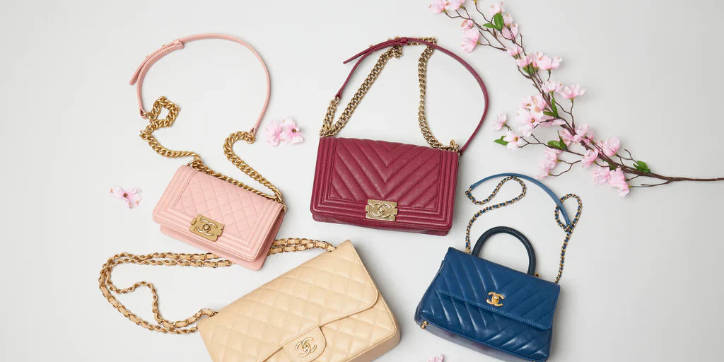 Four Chanel quilted leather handbags in pink, burgundy, beige, and blue with gold hardware on white background.