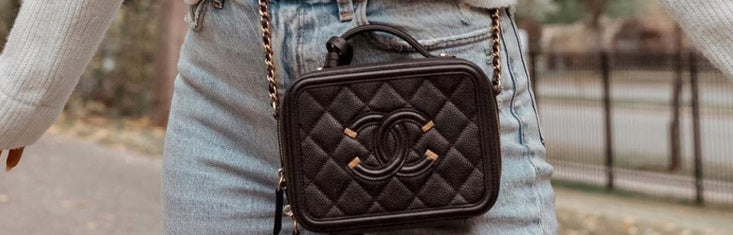 Black quilted leather Chanel vanity bag with gold double C logo and chain strap worn crossbody