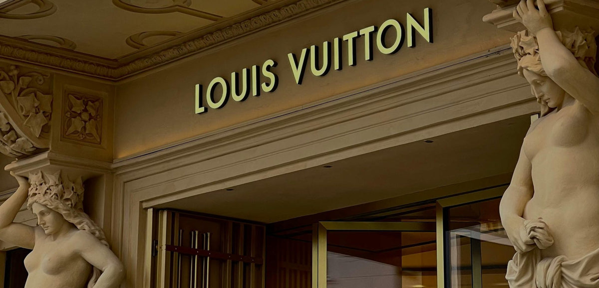 Louis Vuitton store entrance with gold lettering and classical stone sculptures