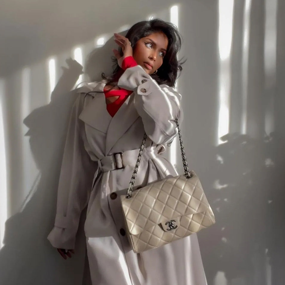 A woman in a white coat carrying a quilted Chanel bag