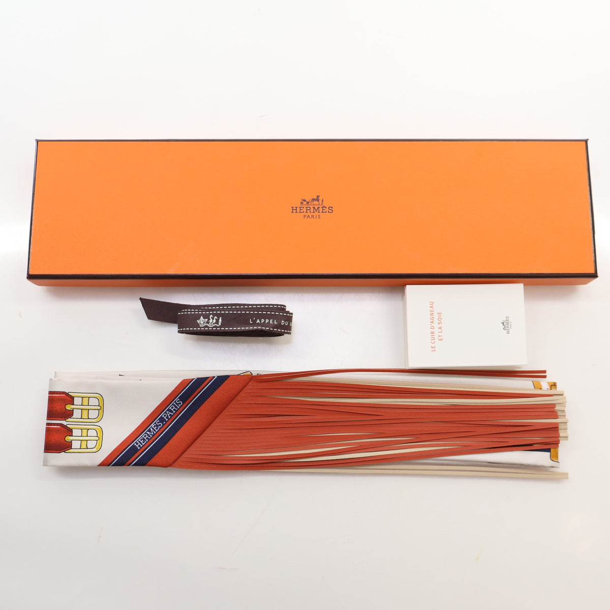 Pre-Owned Hermès Jumping Leather Fringes Twilly, shown with dust bag and packaging